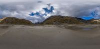 a panoramic view of a mountain range and beach area with sand dunes in front