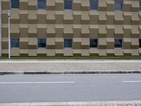 a building made from blocks with multiple windows sitting in front of it on the side of a street