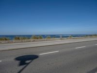 an empty road by the ocean during the day time with no cars on it is clear
