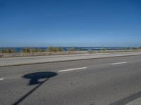 an empty road by the ocean during the day time with no cars on it is clear