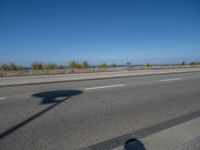 an empty road by the ocean during the day time with no cars on it is clear