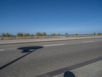 an empty road by the ocean during the day time with no cars on it is clear