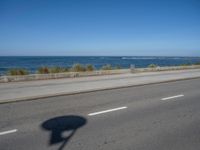 an empty road by the ocean during the day time with no cars on it is clear