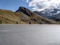 there is a motorcycle that is parked in a road beside the mountains on a sunny day