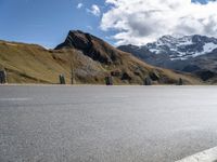 there is a motorcycle that is parked in a road beside the mountains on a sunny day