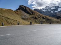 there is a motorcycle that is parked in a road beside the mountains on a sunny day