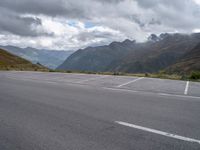 a motorcycle parked in an empty parking lot between mountains in the mountains on a cloudy day