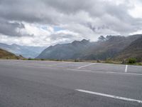 a motorcycle parked in an empty parking lot between mountains in the mountains on a cloudy day