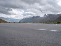 a motorcycle parked in an empty parking lot between mountains in the mountains on a cloudy day