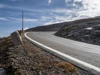 a small rocky hill is behind the curve of a road as it winds across the side