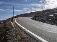 a small rocky hill is behind the curve of a road as it winds across the side