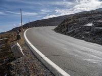 a small rocky hill is behind the curve of a road as it winds across the side