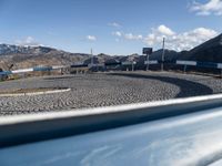 a car at the entrance to a large industrial site in a mountainous area with mountains in the background