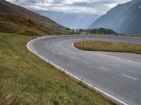 an empty road with two white arrows leading into the mountains and two hills behind it