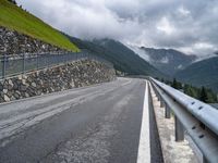 mountains with a fence separating it and the road beside it to a cliff, below them