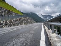 mountains with a fence separating it and the road beside it to a cliff, below them