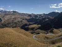 the road is going through a mountain valley on it's side, with mountains in the background