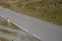 an image of a hill with a road passing by it and a dog standing by the side of a road