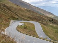 the truck is going around the bend of the hill road between hills and grass and the road is winding through the hills