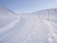 a young man on a snow board on a snowy hill during the day, with a trail behind him in deep snow