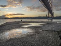 sunset with sky and water reflecting the silhouette of the bay bridge, bay, or shore