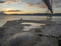 sunset with sky and water reflecting the silhouette of the bay bridge, bay, or shore