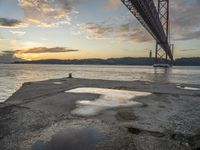 sunset with sky and water reflecting the silhouette of the bay bridge, bay, or shore