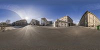 the view from a fisheye lens of an empty street in a european city, with buildings and a person riding on a bike