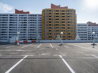 an empty parking lot near some high rise buildings in the sun lightening in a clear blue sky