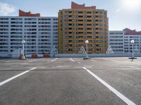 an empty parking lot near some high rise buildings in the sun lightening in a clear blue sky