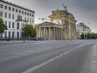 an empty street in front of two large buildings and a statue on a steeple