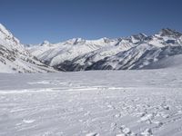 person on skis on slope with snow mountains in background / snowy slopes and ski tracks in foreground