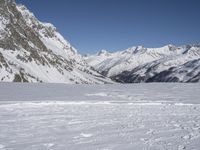 person on skis on slope with snow mountains in background / snowy slopes and ski tracks in foreground