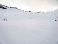 a man on skis going down the side of a snowy hill near some ski lift poles