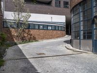 the street is paved with rocks and grass in front of a building and a walkway near the building