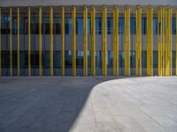 a concrete structure made into rows of orange and yellow poles are on a cement sidewalk