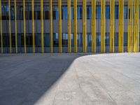 a concrete structure made into rows of orange and yellow poles are on a cement sidewalk