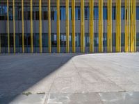 a concrete structure made into rows of orange and yellow poles are on a cement sidewalk