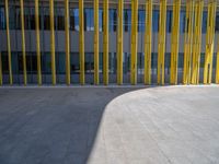 a concrete structure made into rows of orange and yellow poles are on a cement sidewalk