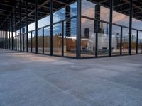 empty city building has glass and metal panels on the front of it, with an outside courtyard