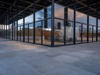 empty city building has glass and metal panels on the front of it, with an outside courtyard