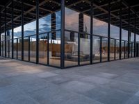 empty city building has glass and metal panels on the front of it, with an outside courtyard