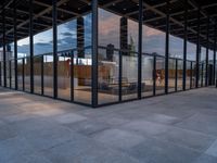 empty city building has glass and metal panels on the front of it, with an outside courtyard