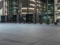 a very big square with some stairs and windows at night time with a fire hydrant sitting in front of it