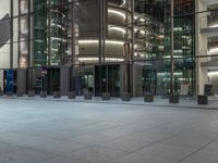 a very big square with some stairs and windows at night time with a fire hydrant sitting in front of it