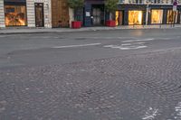 a street that has two buildings on it and the sidewalk has brick pavers in it