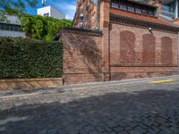 a long empty brick street with tall buildings in the background on a sunny day with some people walking around