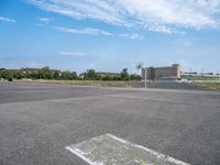 a empty lot with parking and some buildings in the background on a sunny day with blue sky