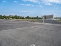 a empty lot with parking and some buildings in the background on a sunny day with blue sky