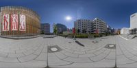 there is a circular panorama in a city square with buildings and a statue on the pavement